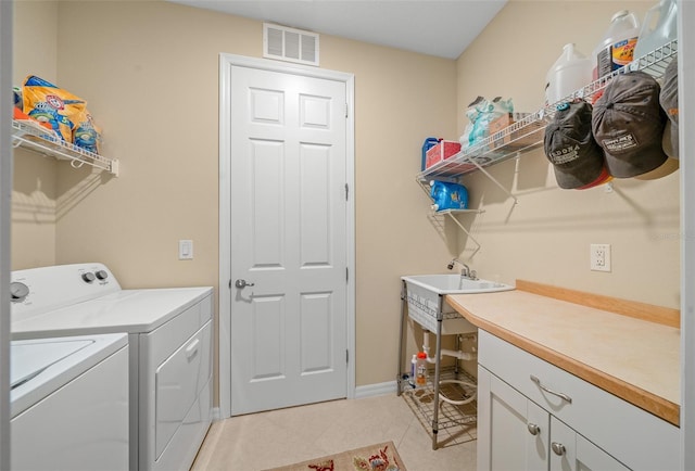 laundry room with washer and dryer, light tile patterned flooring, cabinets, and sink