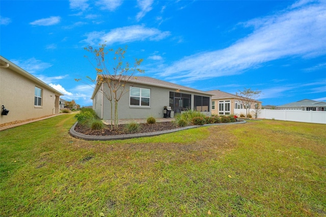 back of property with a yard and a sunroom