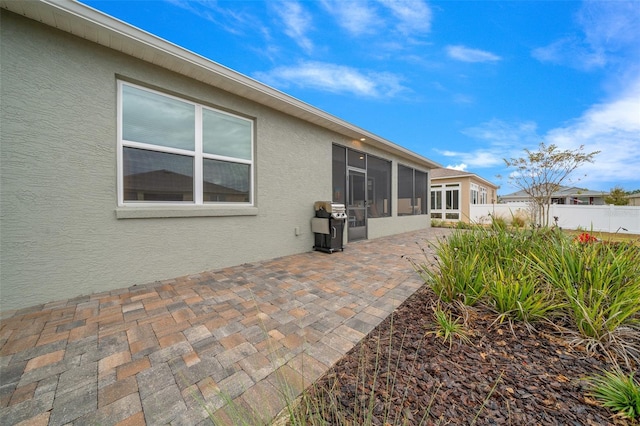 rear view of house featuring a sunroom and a patio area