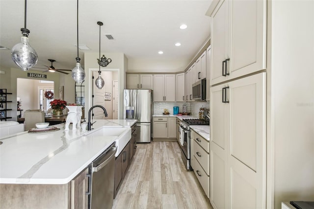 kitchen featuring a large island, sink, ceiling fan, pendant lighting, and appliances with stainless steel finishes