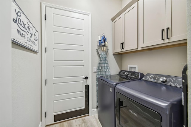 laundry area with separate washer and dryer, light hardwood / wood-style flooring, and cabinets