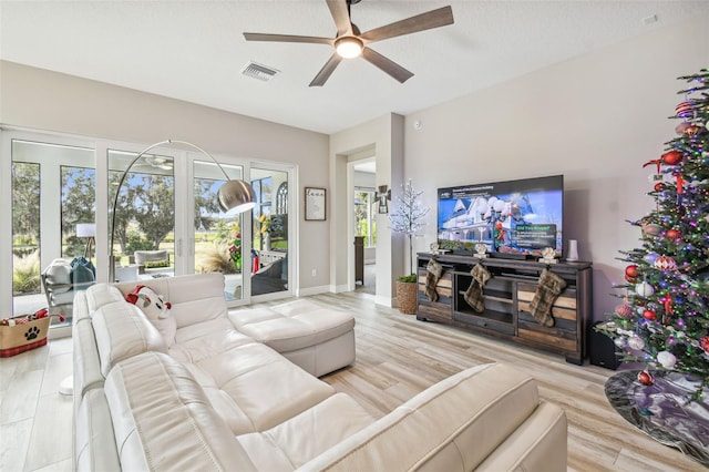 living room featuring ceiling fan, light wood-type flooring, and a textured ceiling