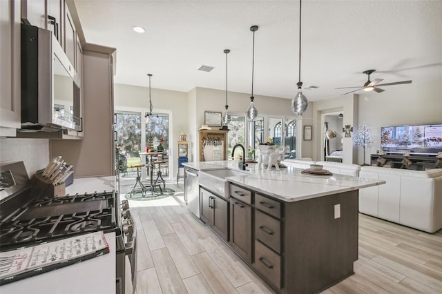 kitchen with plenty of natural light, sink, stainless steel appliances, and an island with sink