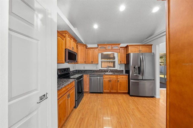 kitchen with appliances with stainless steel finishes, a textured ceiling, sink, light hardwood / wood-style floors, and lofted ceiling