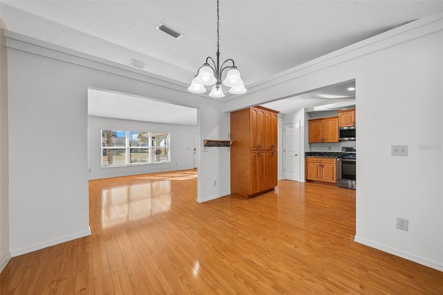 interior space with hanging light fixtures, a textured ceiling, light hardwood / wood-style floors, stainless steel appliances, and a chandelier