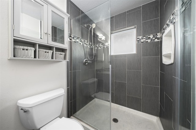 bathroom featuring toilet, a textured ceiling, and a tile shower