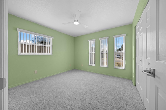 carpeted empty room featuring ceiling fan and a textured ceiling