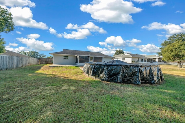 back of property with a yard and a covered pool