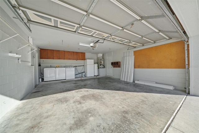 garage featuring washing machine and dryer, white fridge, and a garage door opener