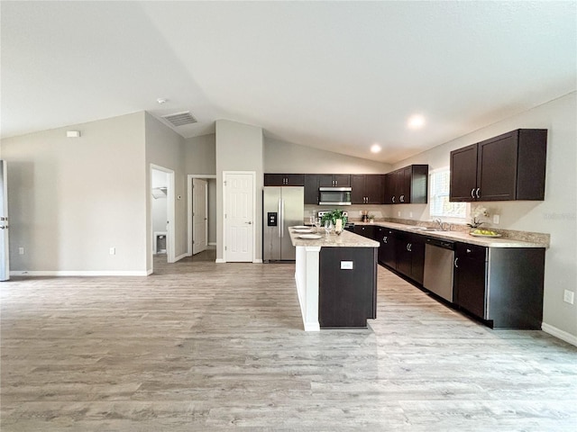 kitchen with stainless steel appliances, sink, light hardwood / wood-style floors, a kitchen island, and lofted ceiling