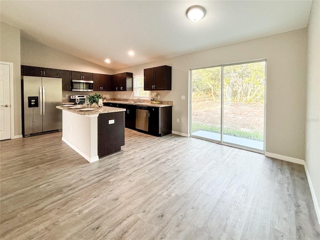 kitchen with stainless steel appliances, vaulted ceiling, sink, light hardwood / wood-style flooring, and a kitchen island