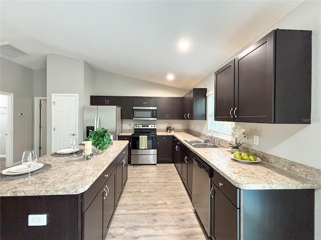 kitchen featuring stainless steel appliances, sink, light hardwood / wood-style flooring, a center island, and lofted ceiling