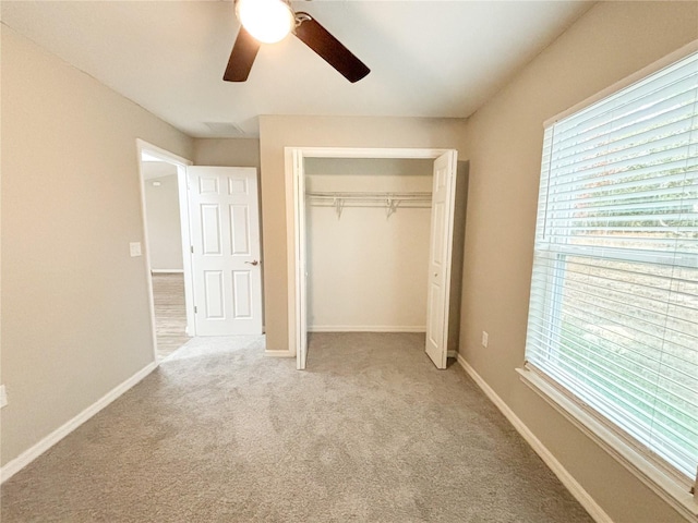 unfurnished bedroom featuring multiple windows, carpet floors, a closet, and ceiling fan