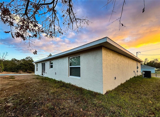 property exterior at dusk with a yard and cooling unit