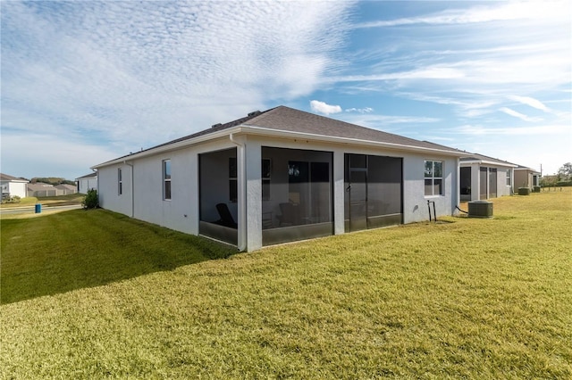 rear view of property featuring cooling unit, a yard, and a sunroom