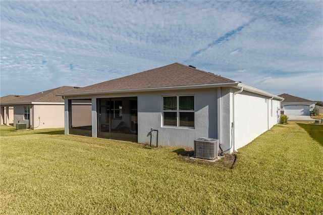 rear view of house featuring central AC, a sunroom, and a lawn