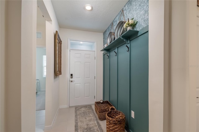 mudroom with a textured ceiling and light tile patterned floors