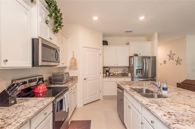 kitchen featuring stainless steel appliances, sink, white cabinetry, light stone counters, and light tile patterned floors