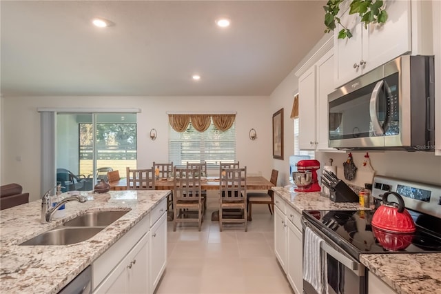 kitchen with light stone counters, stainless steel appliances, light tile patterned floors, white cabinets, and sink