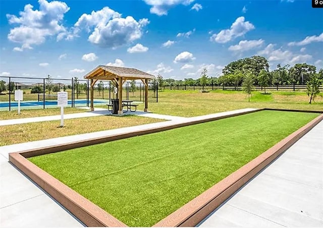 view of community with tennis court, a lawn, and a gazebo