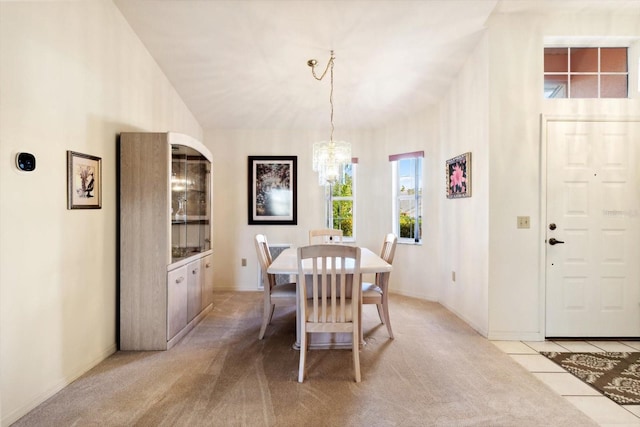 dining area with light carpet and an inviting chandelier