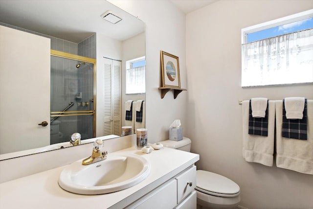 bathroom with walk in shower, vanity, and toilet