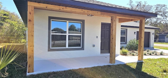 doorway to property with roof with shingles and stucco siding