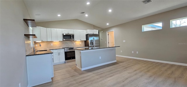 kitchen featuring stainless steel appliances, a kitchen island, a sink, visible vents, and white cabinetry