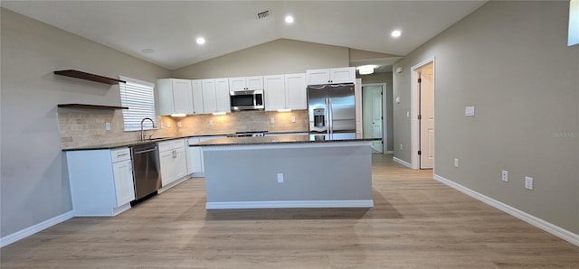 kitchen featuring appliances with stainless steel finishes, white cabinets, a kitchen island, and open shelves