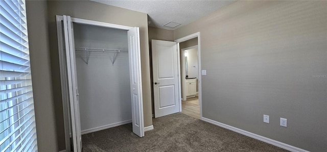 unfurnished bedroom with carpet, a closet, a textured ceiling, and baseboards