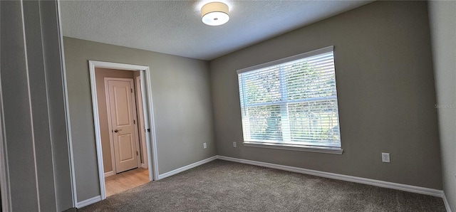 empty room with a textured ceiling, carpet floors, and baseboards