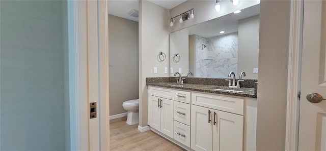 bathroom featuring toilet, a shower, a sink, and visible vents