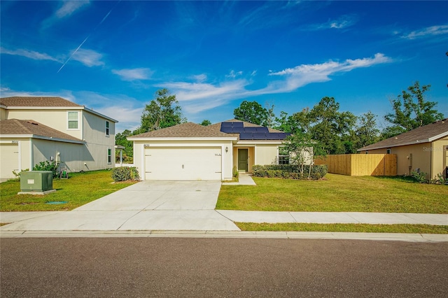 view of front of house featuring central AC unit, a garage, a front yard, and solar panels