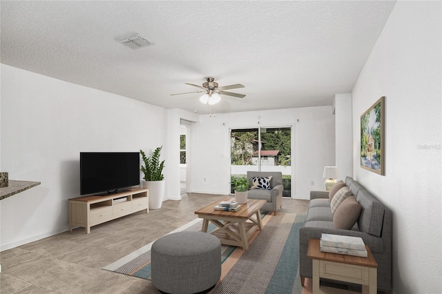 living room featuring ceiling fan and a textured ceiling