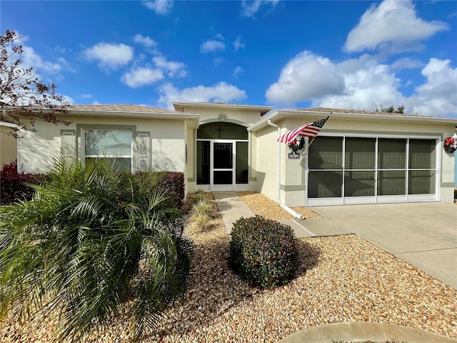 view of front facade with a garage, driveway, and stucco siding