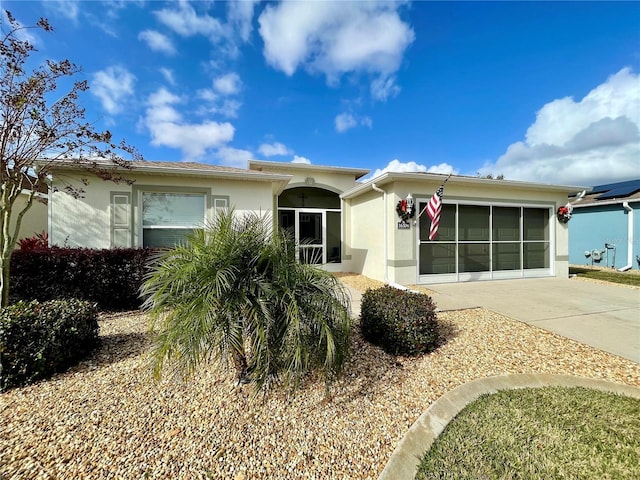 view of front of property featuring concrete driveway, an attached garage, and stucco siding