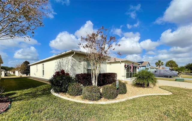 view of home's exterior featuring concrete driveway, a lawn, and stucco siding