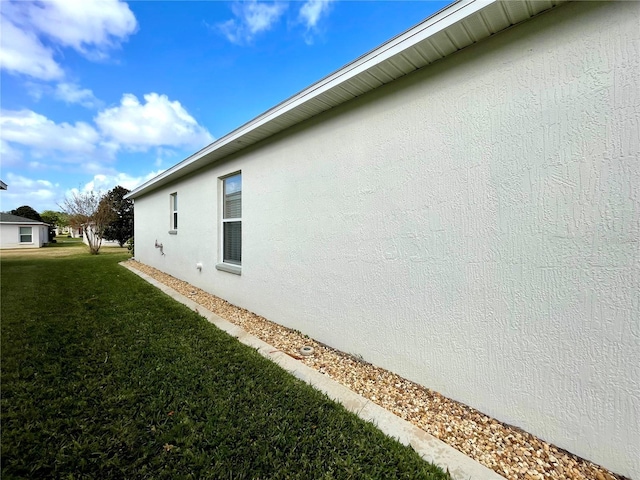 view of side of property with a yard and stucco siding