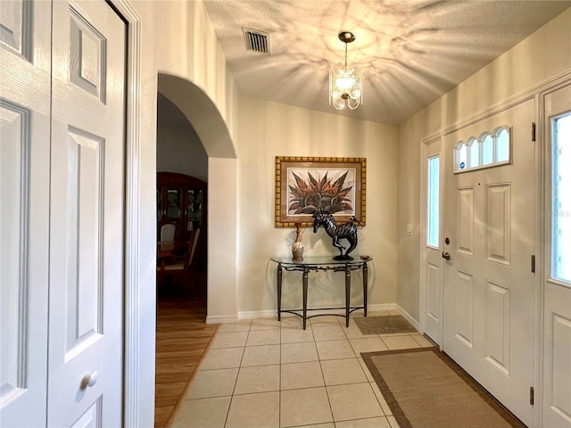 entryway featuring visible vents, arched walkways, baseboards, a wealth of natural light, and light tile patterned flooring