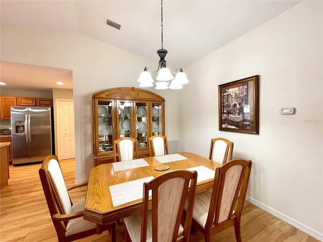 dining area with lofted ceiling, light wood-style floors, visible vents, and a chandelier