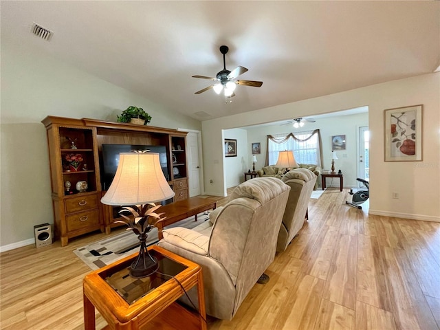 living room featuring a ceiling fan, visible vents, vaulted ceiling, baseboards, and light wood finished floors