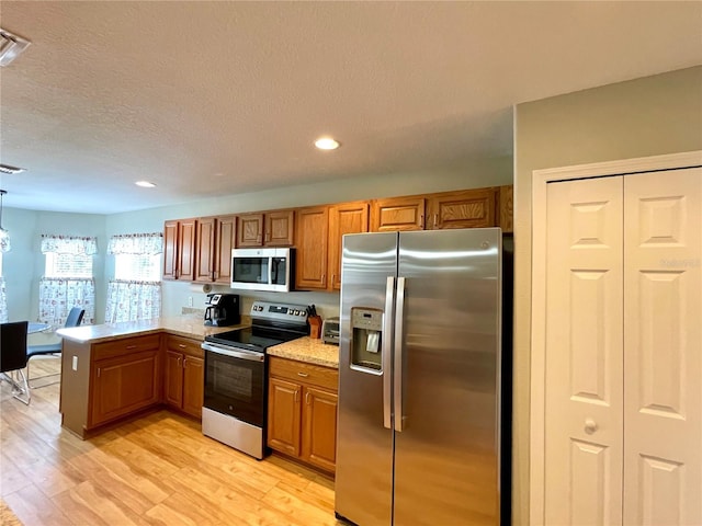 kitchen featuring a peninsula, brown cabinetry, stainless steel appliances, and light wood-style floors