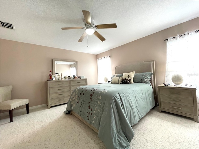 bedroom featuring visible vents, light carpet, ceiling fan, a textured ceiling, and baseboards