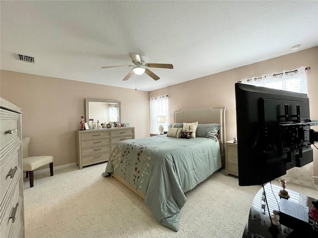 bedroom with a ceiling fan, visible vents, a textured ceiling, and light colored carpet