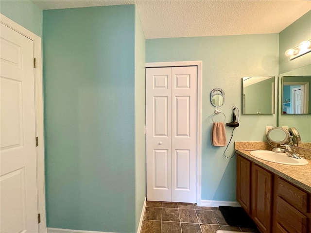 bathroom featuring a closet, baseboards, a textured ceiling, and vanity