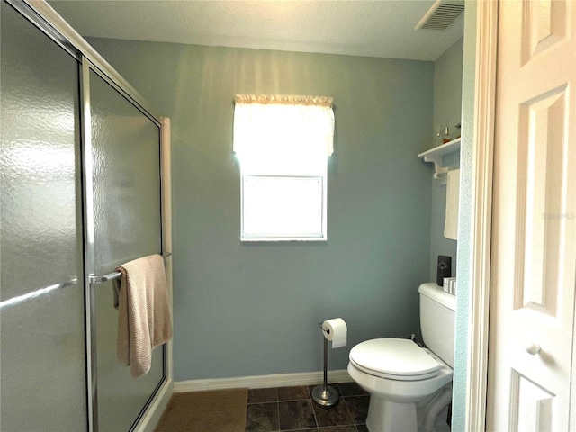 bathroom featuring tile patterned flooring, toilet, visible vents, baseboards, and a stall shower