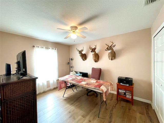 office space with visible vents, ceiling fan, a textured ceiling, and wood finished floors