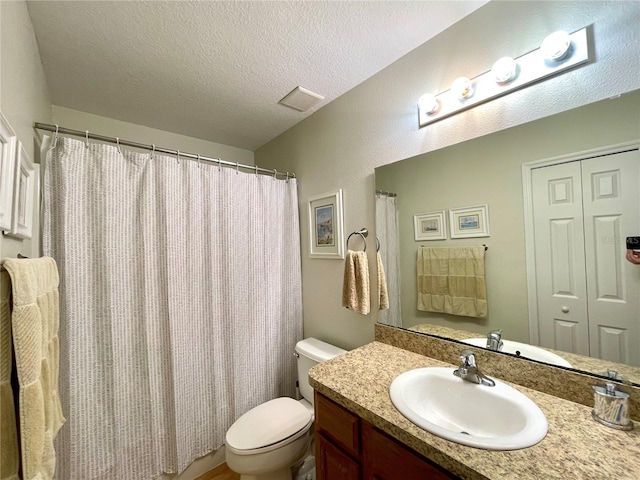 bathroom featuring toilet, a textured ceiling, vanity, and visible vents