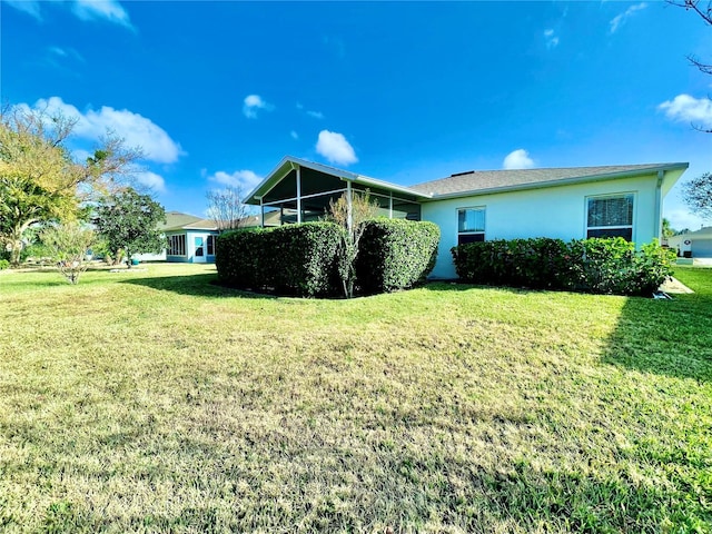 rear view of property with a sunroom, a lawn, and stucco siding