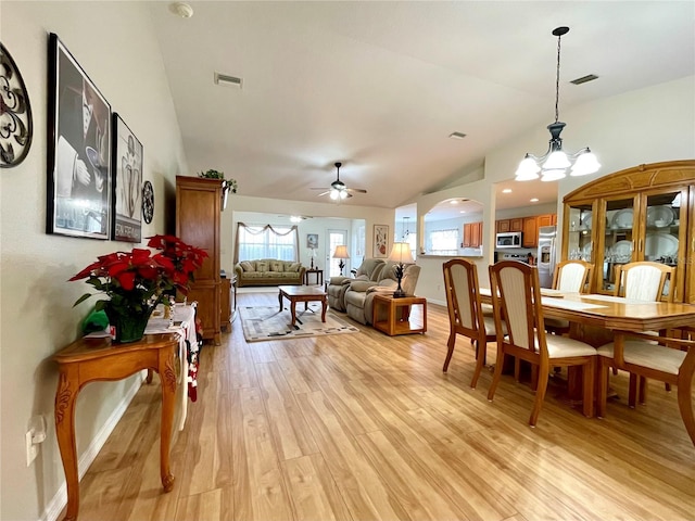 dining space with ceiling fan with notable chandelier, a healthy amount of sunlight, visible vents, and light wood-style floors